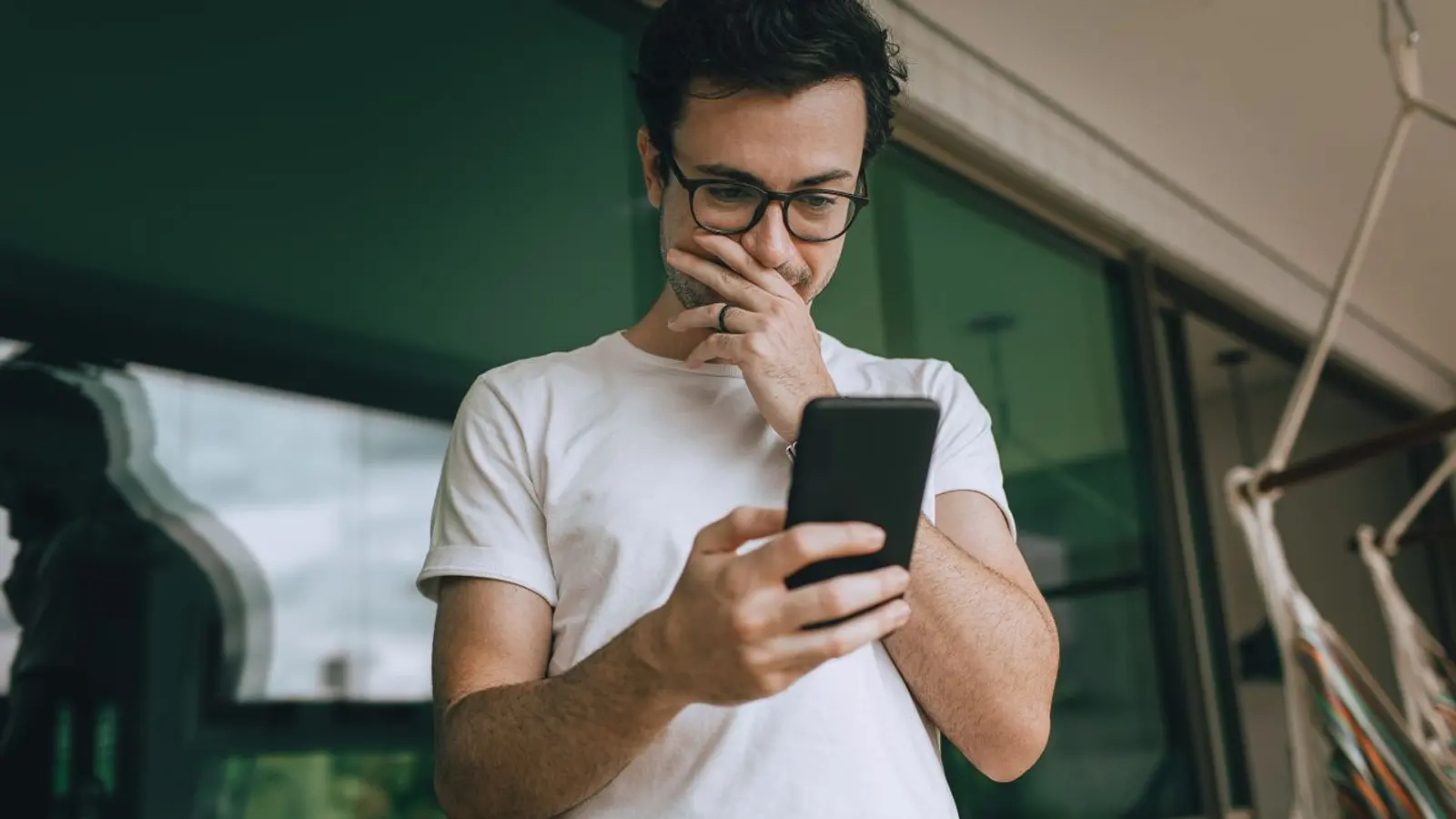 Hombre pensativo mirando el teléfono, como quien busca un negocio en Google.